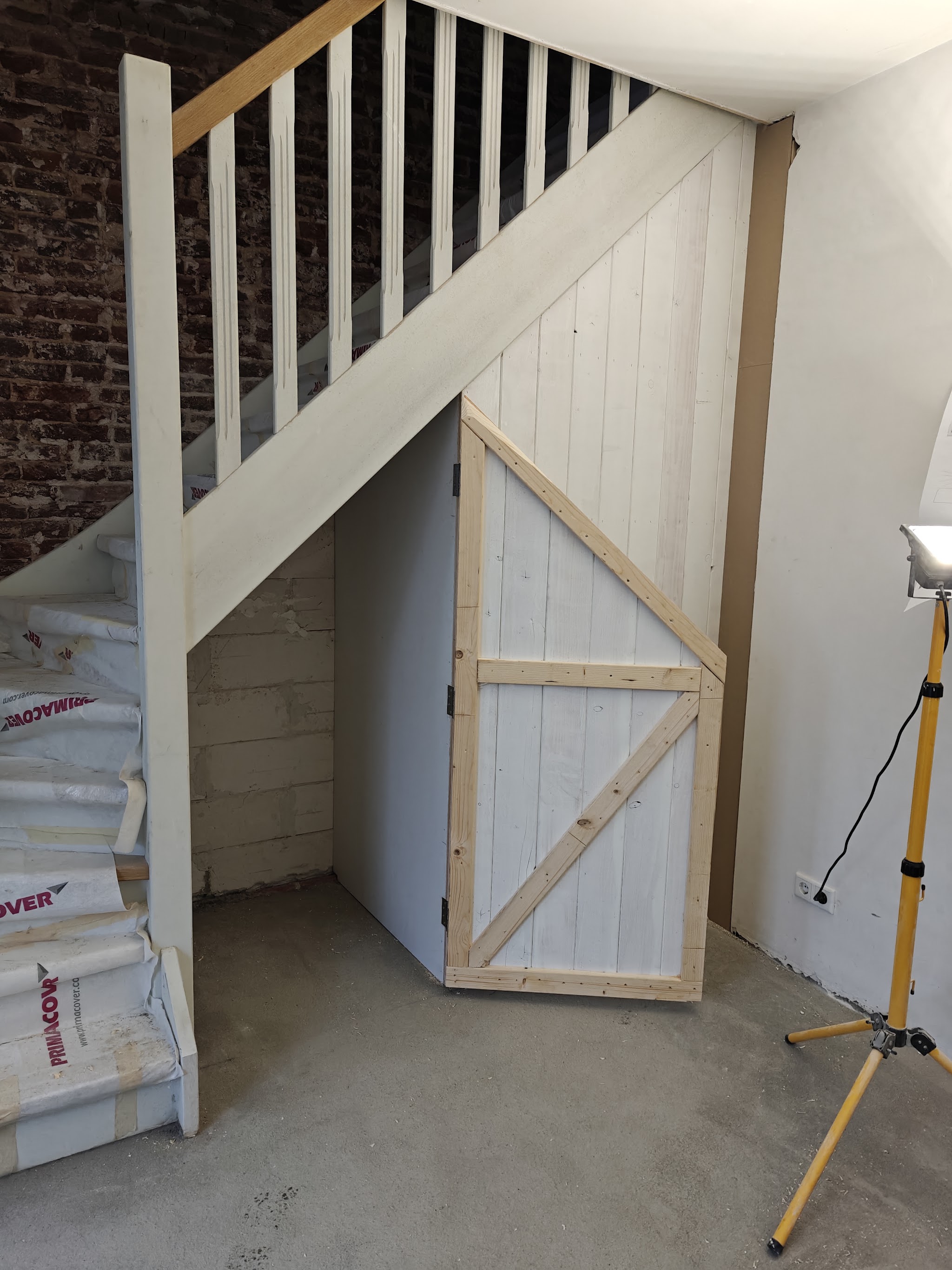 Trap met een nieuwe houten deur in de kast onder de trap