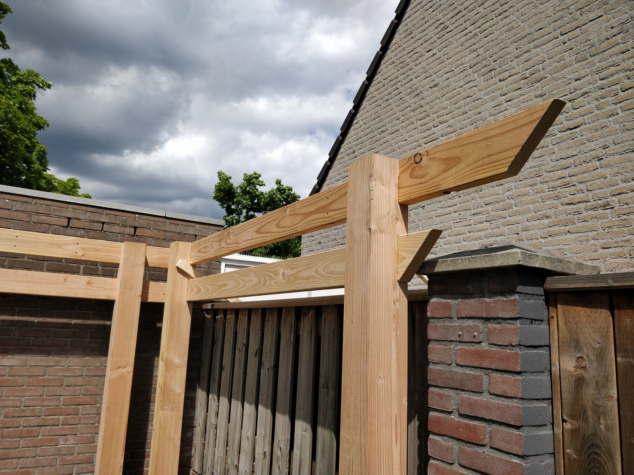 Nieuw douglas balkenframe tegen een bakstenen huis en schutting